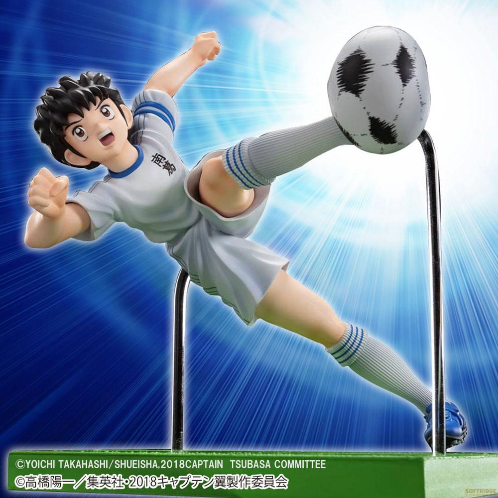Anime-Fußballspieler in weißer Uniform schießt Ball vor blauem Hintergrund.
