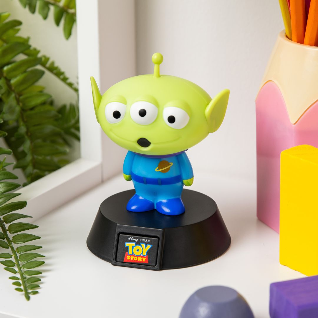 Zielona figurka kosmity Toy Story z trzema oczami w niebieskim uniformie na czarnej podstawie.