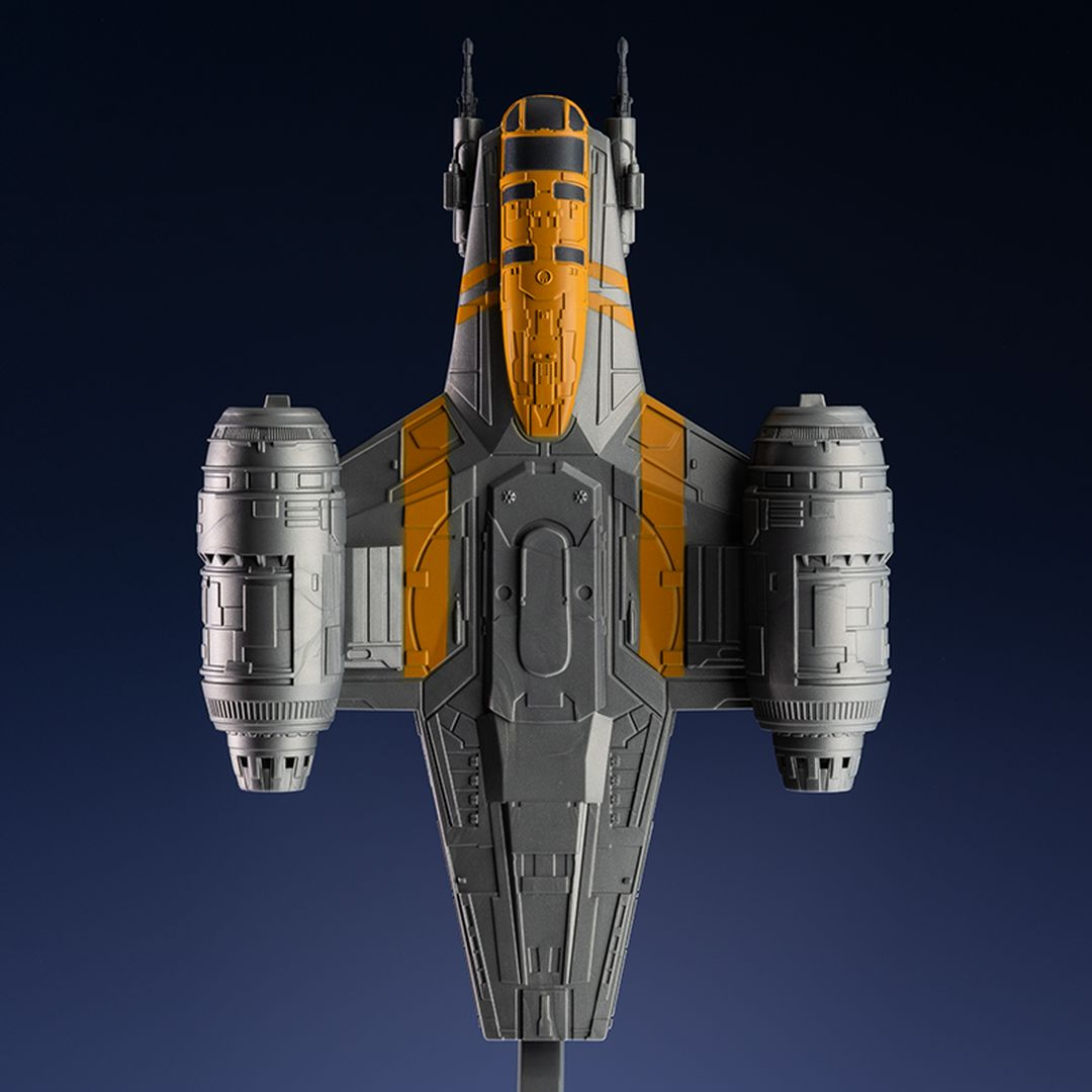Una nave espacial gris con detalles naranjas sobre un fondo azul oscuro.