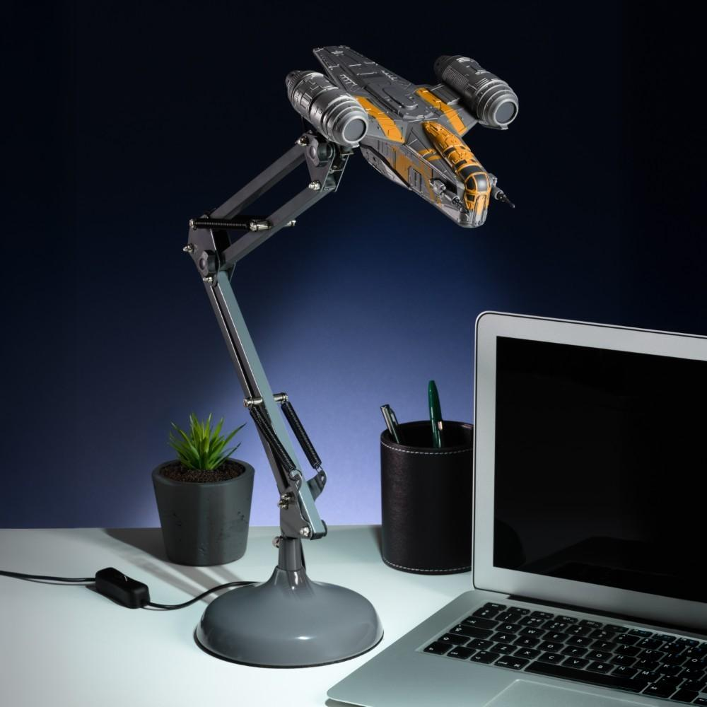 Escritorio con portátil, lámpara de nave espacial, planta y portalápices.