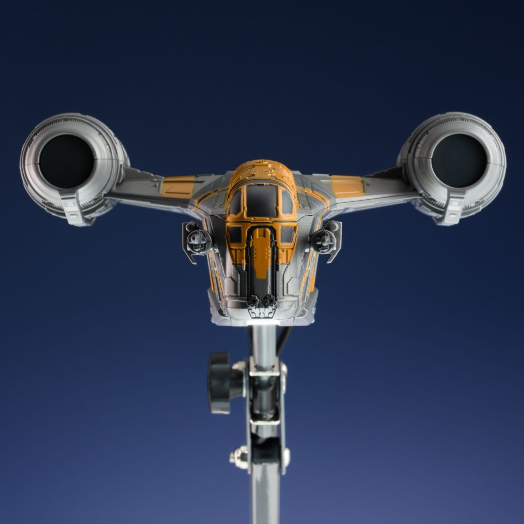 Un modelo de nave espacial gris y amarillo con dos motores sobre fondo azul.