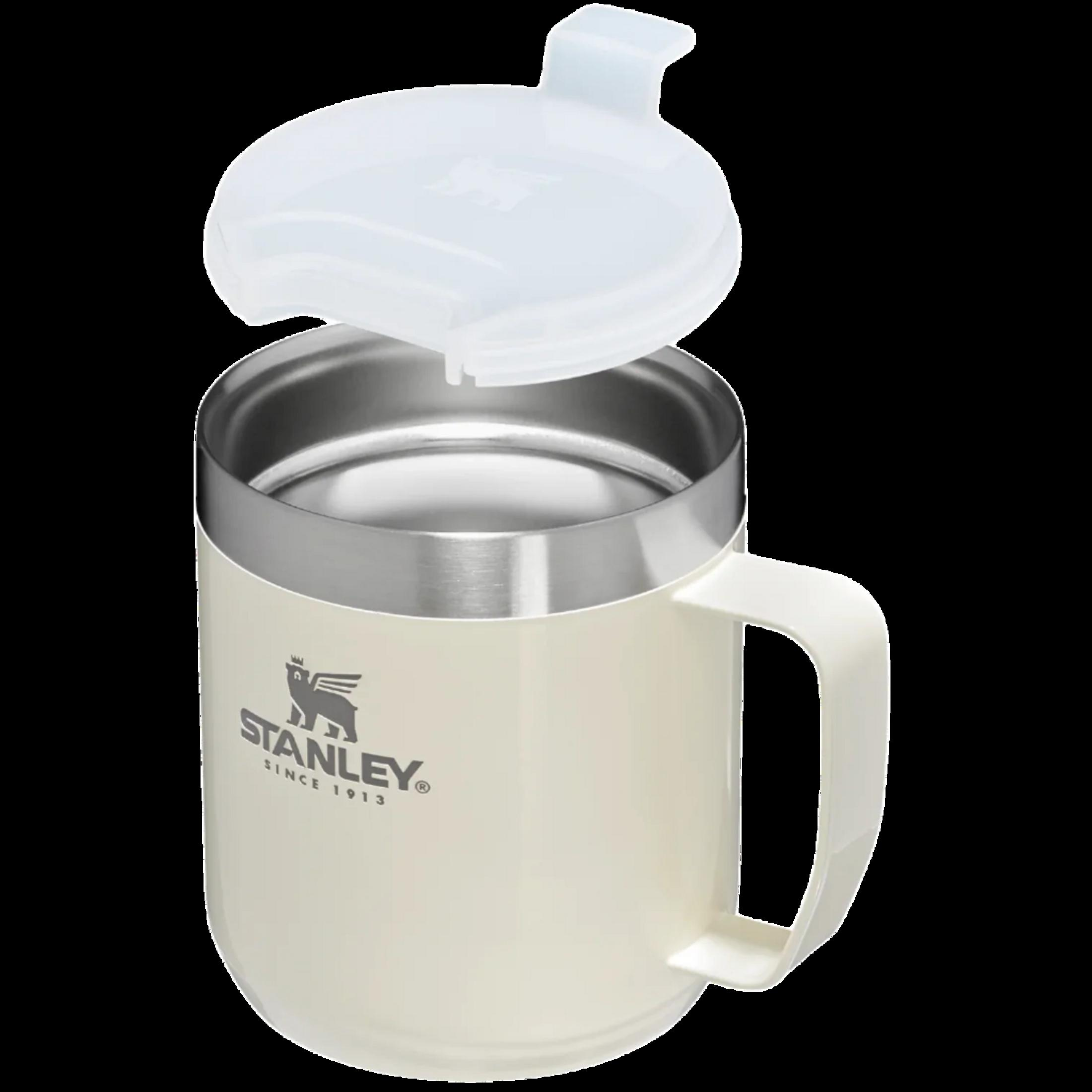 Une tasse Stanley crème avec un bord argenté et un couvercle blanc est ouverte.