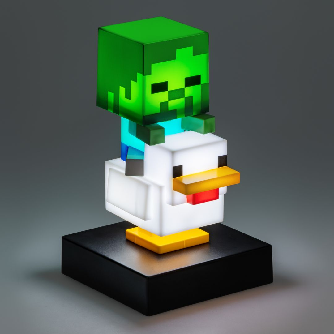 Figurka zombie z Minecraft siedzi na białej figurce kurczaka, na czarnej podstawie.