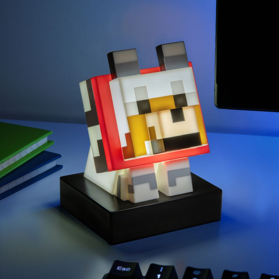 Lampka Minecraft w kształcie wilka stoi na czarnej podstawie. Obok są książki.