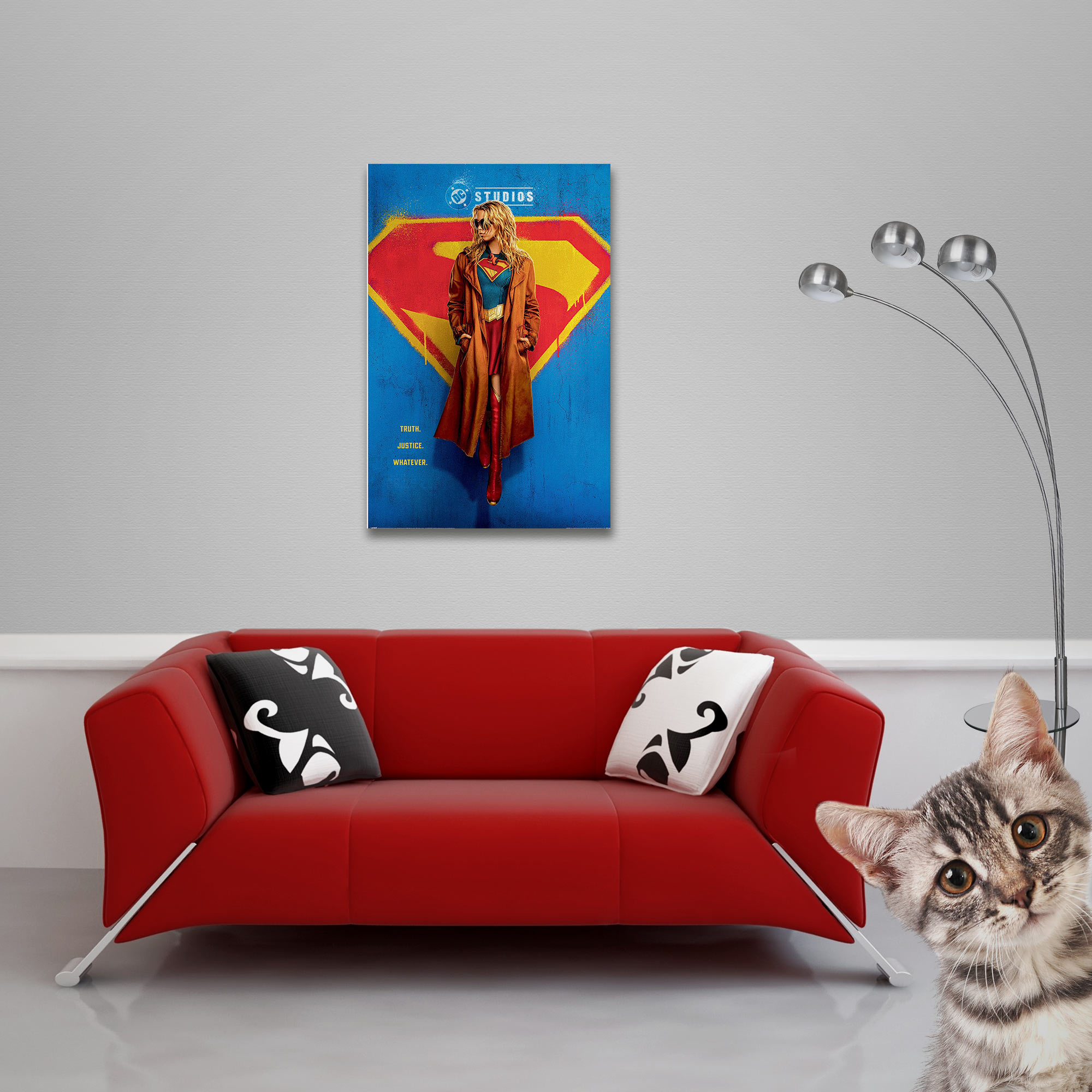 Ein rotes Sofa mit Kissen steht vor einem Superman-Poster. Eine Katze schaut aus der Ecke.