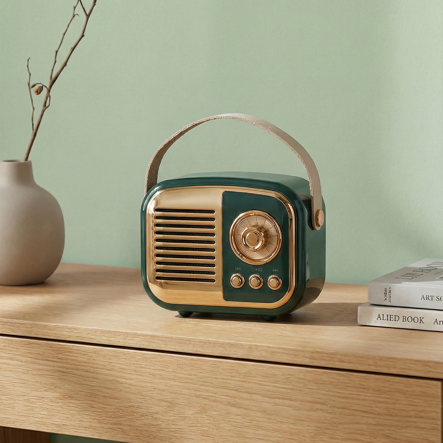 Altın vurgulu vintage yeşil radyo, vazo ve kitapların yanında ahşap bir masanın üzerinde duruyor.