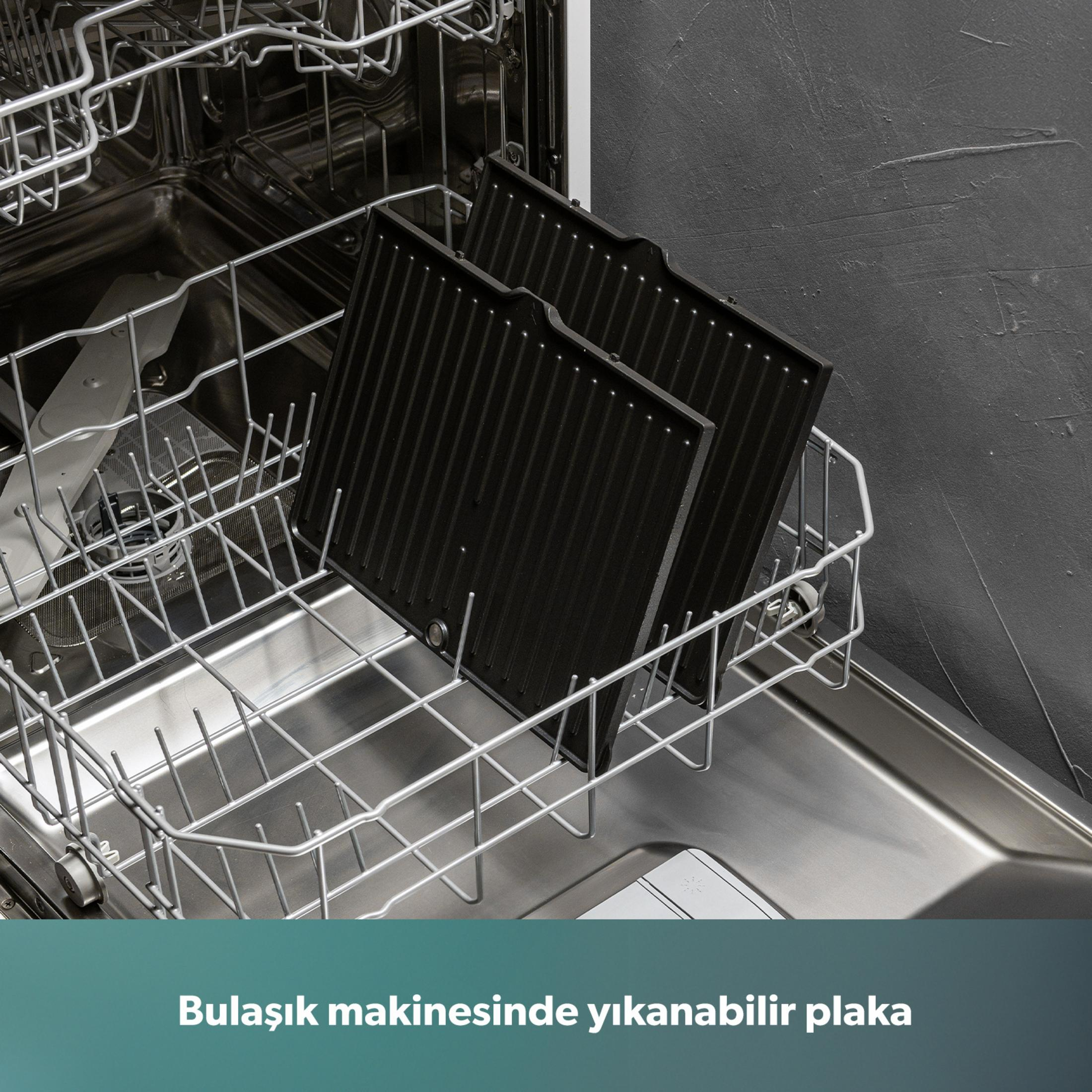 İki siyah ızgara tabağı açık bir bulaşık makinesinin üst rafında duruyor.