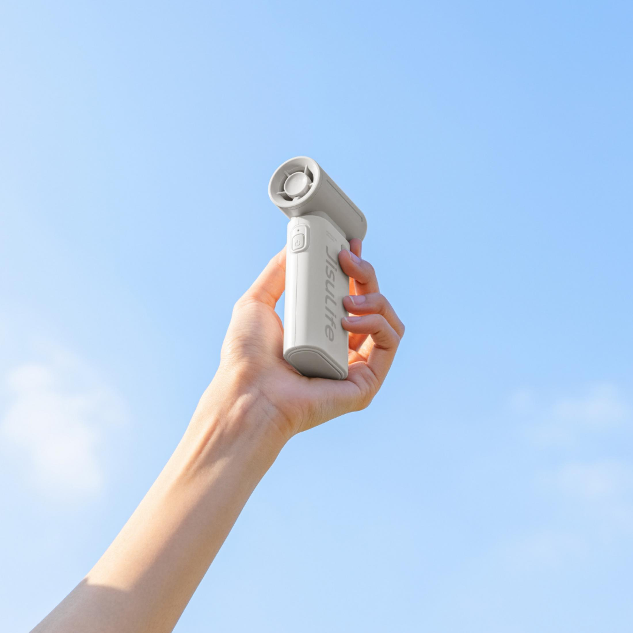 Una mano tiene un ventilatore bianco contro un cielo blu.