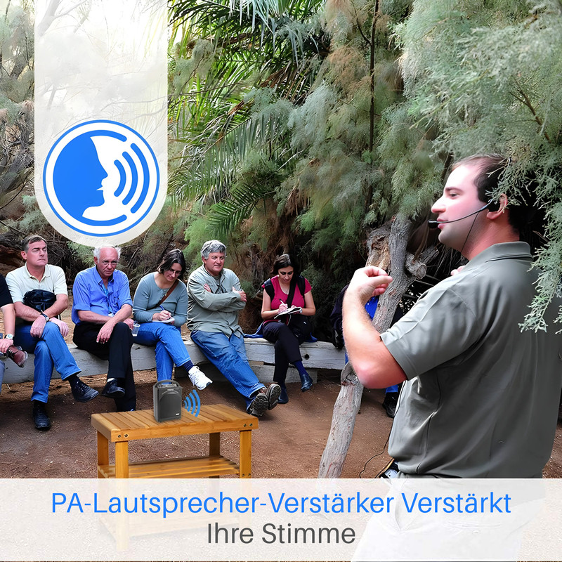 Ein Mann mit Mikrofon spricht zu einer Gruppe sitzender Menschen in einer baumbestandenen Umgebung.