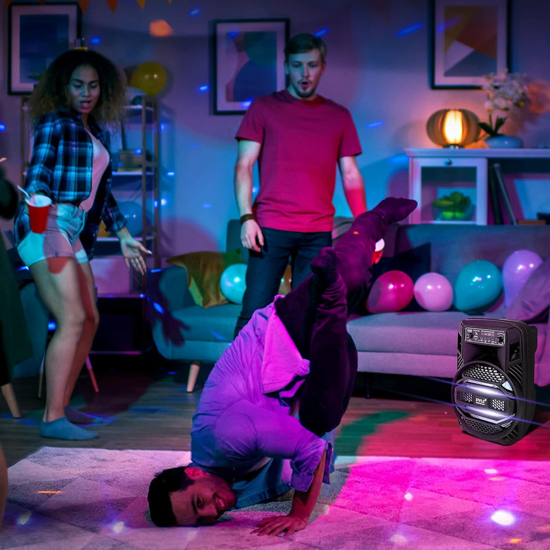 Leute tanzen auf einer Party, ein Mann macht einen Handstand, bunte Lichter.