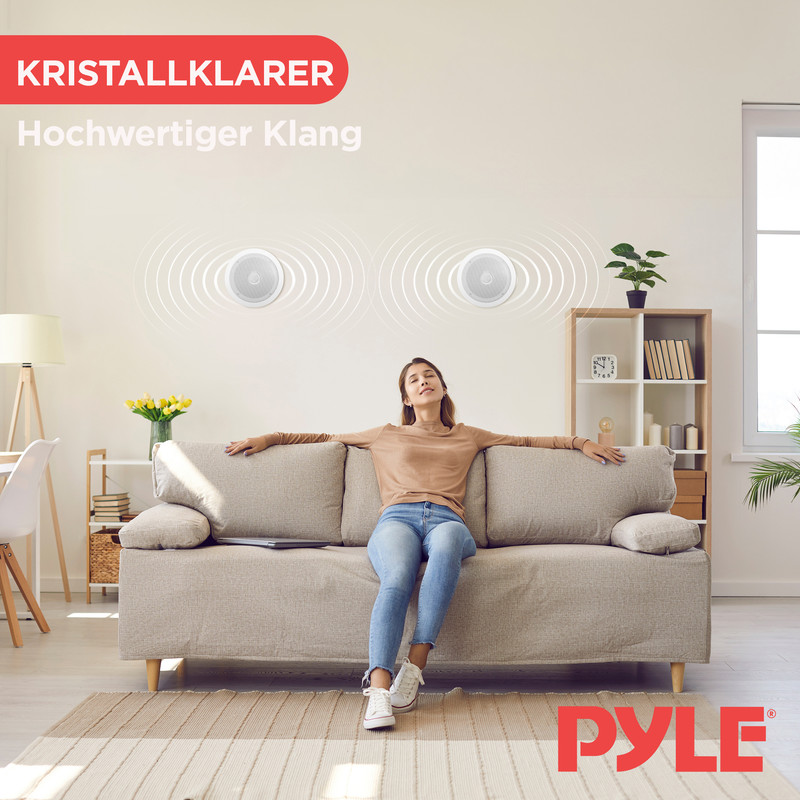 Frau entspannt auf Sofa unter Deckenlautsprechern, Wohnzimmer mit Regal und Lampe.