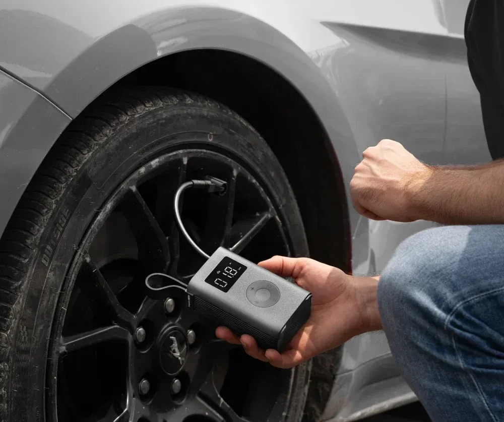 Grauer tragbarer Reifenfüller wird an einem Auto-Rad verwendet.