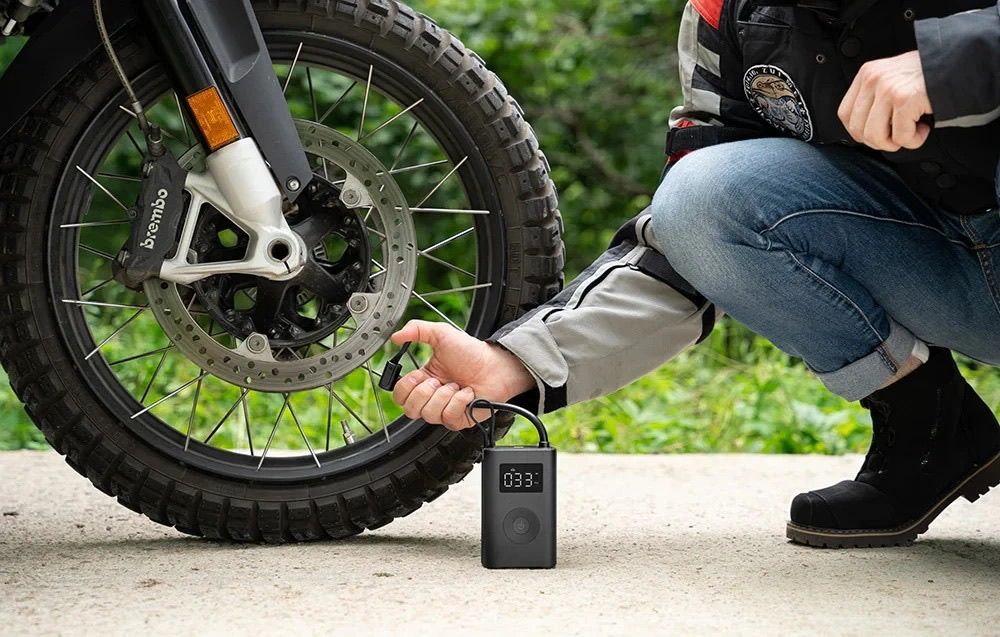 Person pumpt Motorradreifen mit tragbarem Kompressor auf. Nahaufnahme.