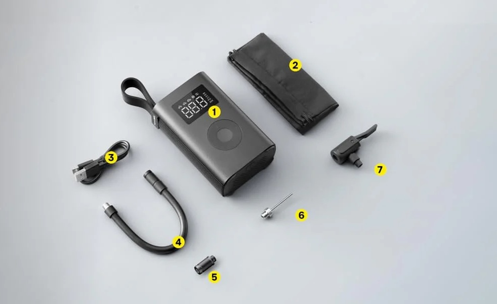 Eine dunkelgraue tragbare Luftpumpe mit Digitalanzeige, Ladekabel, Schlauch, Nadel und Düse.