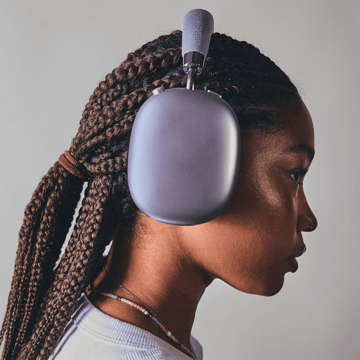 Mujer con pelo trenzado usa auriculares grises. Primer plano.