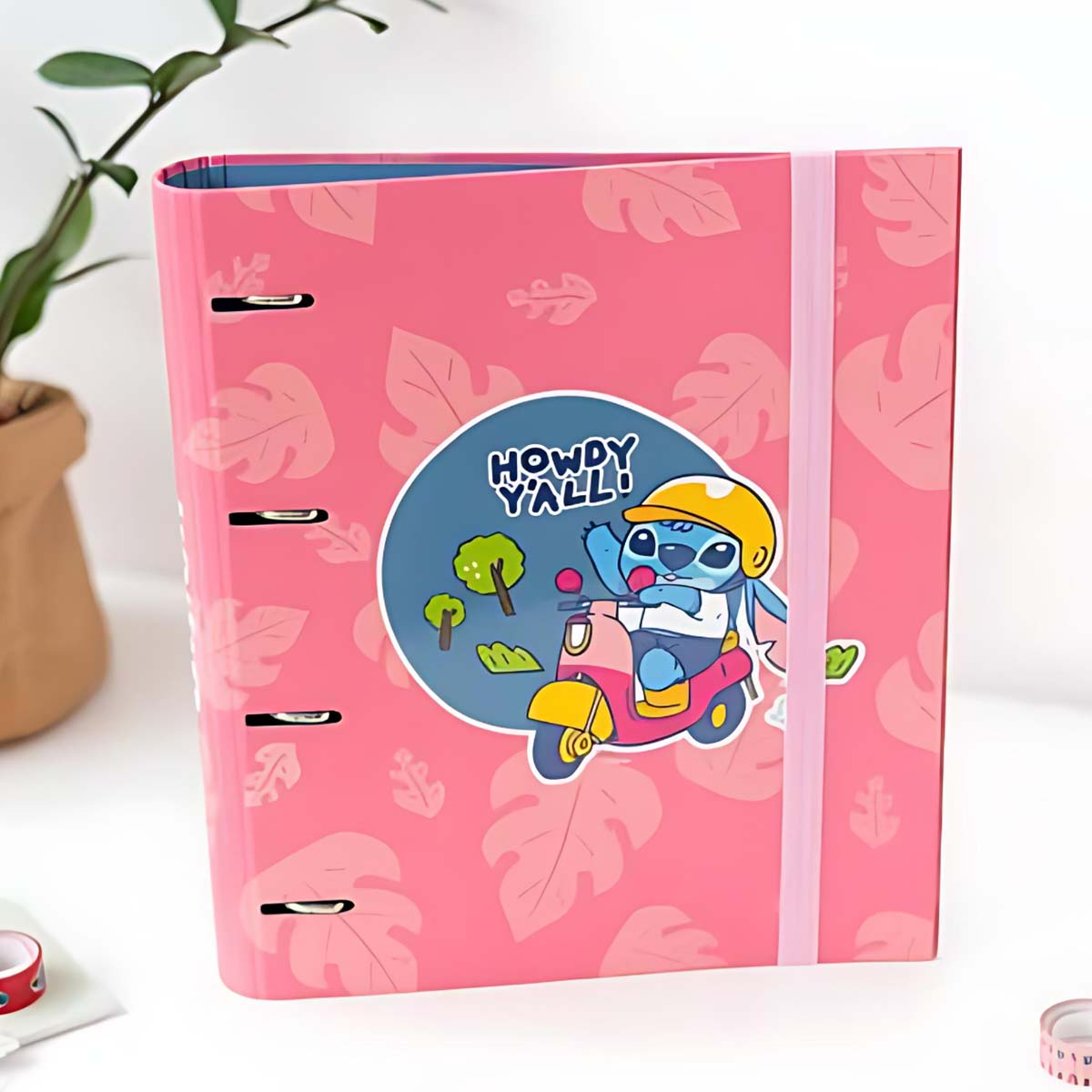 Ein pinker Ordner mit einem Aufkleber von Stitch auf einem Roller. Blättermuster.