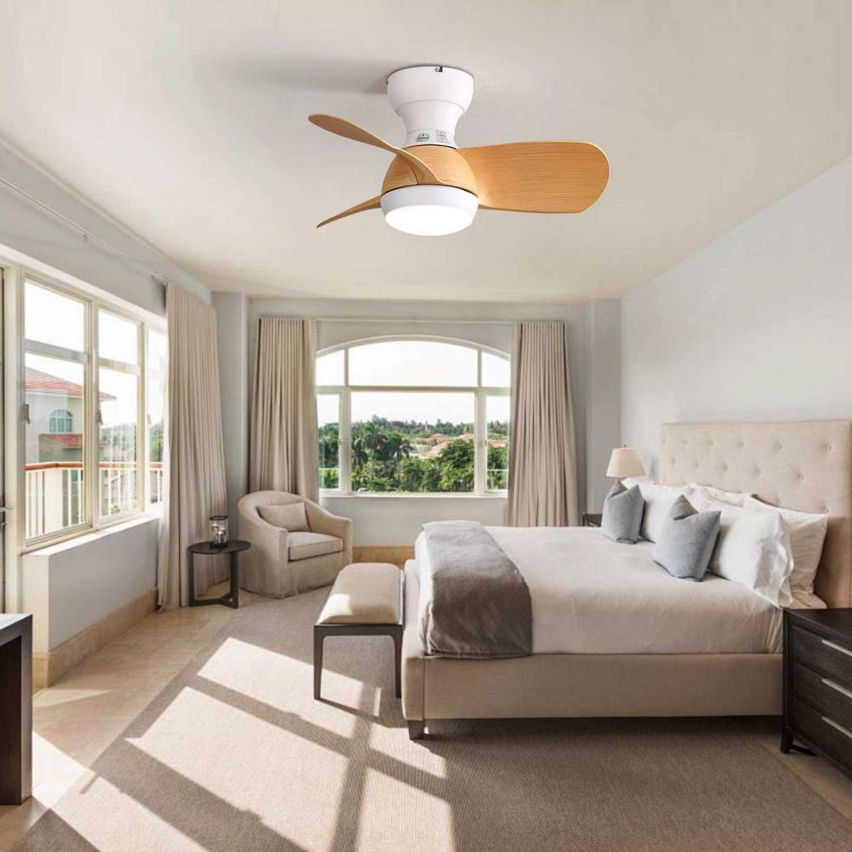 Ein Schlafzimmer mit Bett, Deckenventilator und Fenstern mit Blick auf eine üppige Landschaft.