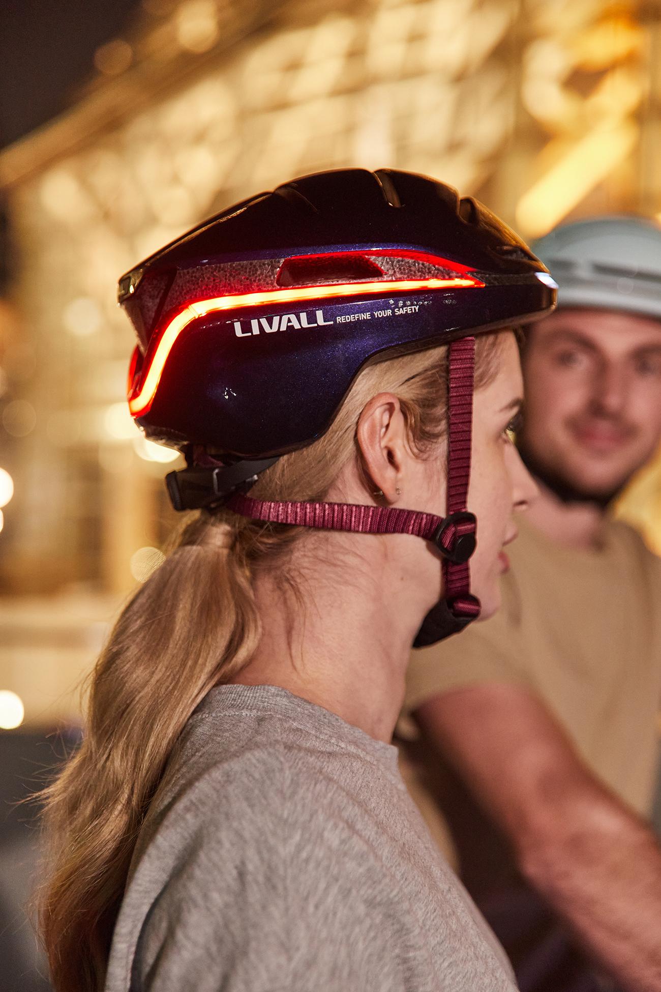 Frau mit blauem Helm und rotem Licht, Mann im Hintergrund.