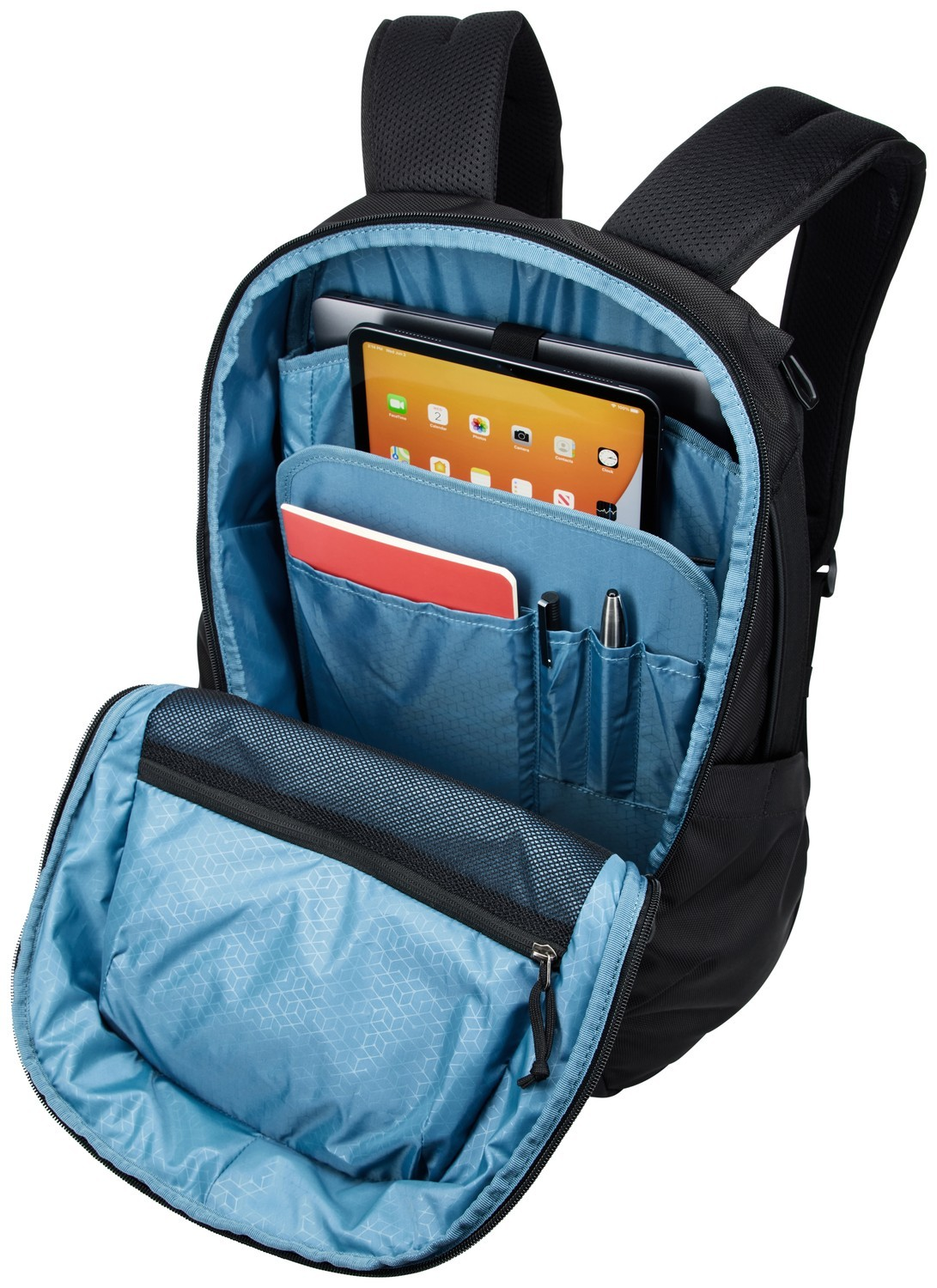 Ein offener schwarzer Rucksack mit blauem Innenfutter, Tablet, Notizbuch und Stiften.