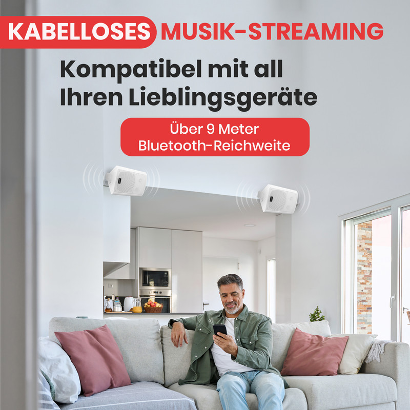 Mann auf Sofa mit Handy, zwei weiße Lautsprecher an Wand. Kabelloses Musikstreaming.