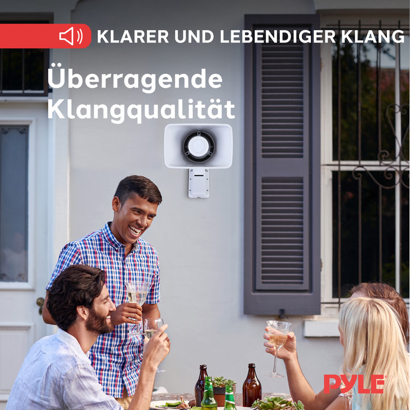 Menschen stoen mit Gläsern an, während ein Lautsprecher an einer Wand montiert ist.