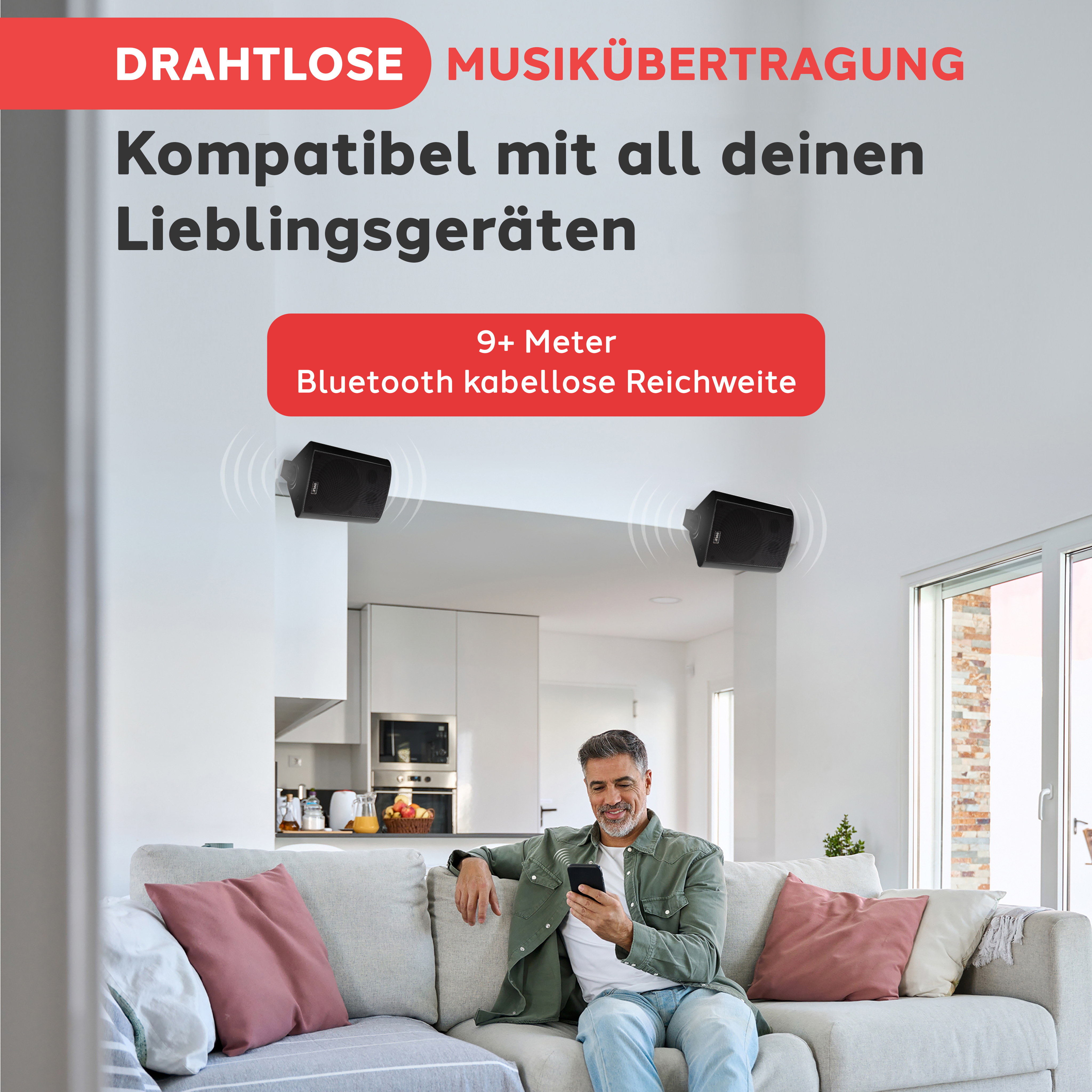 Mann auf Couch mit Handy, zwei schwarze Lautsprecher an der Wand.