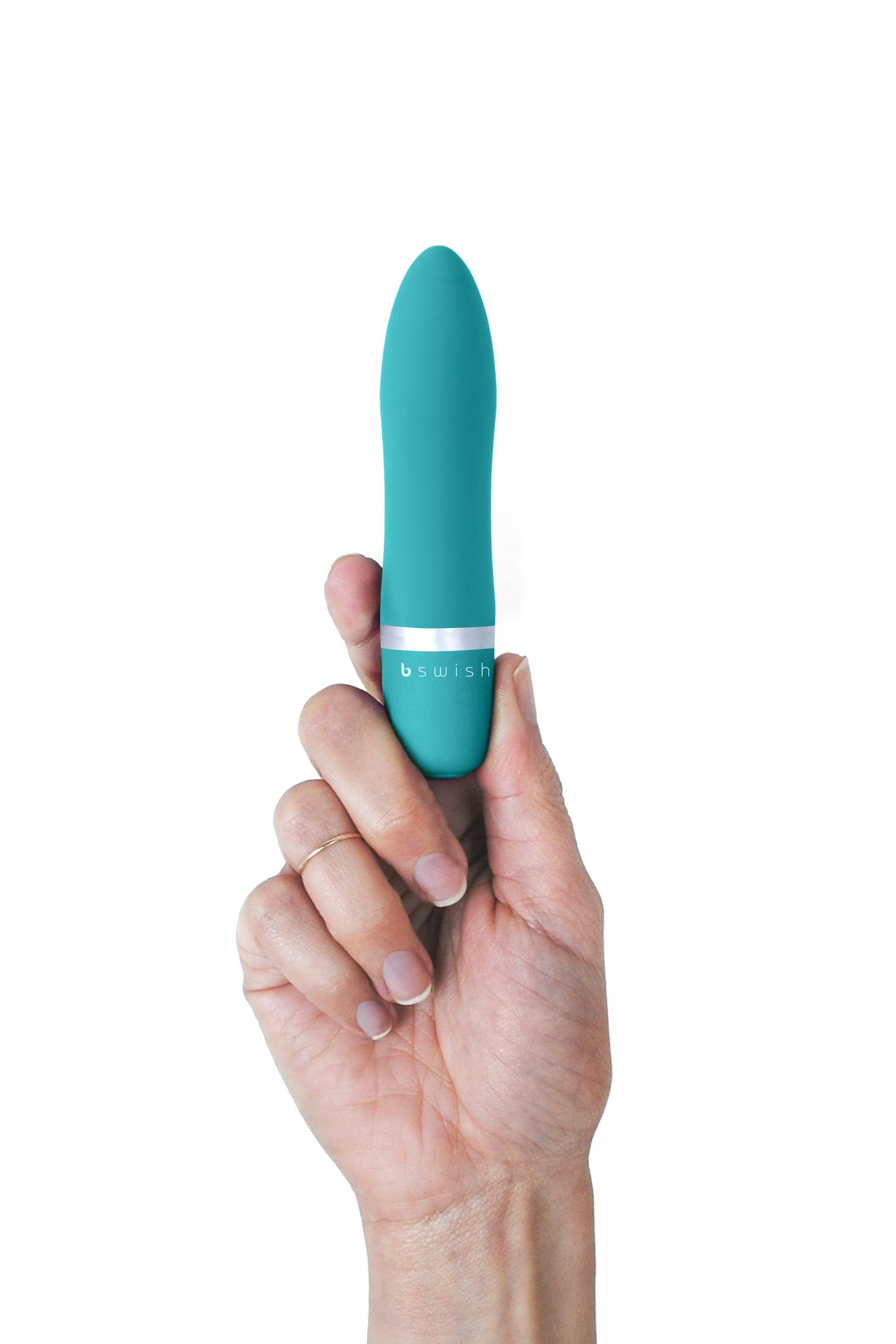 Eine Hand hält einen türkisfarbenen Vibrator mit silbernem Band.