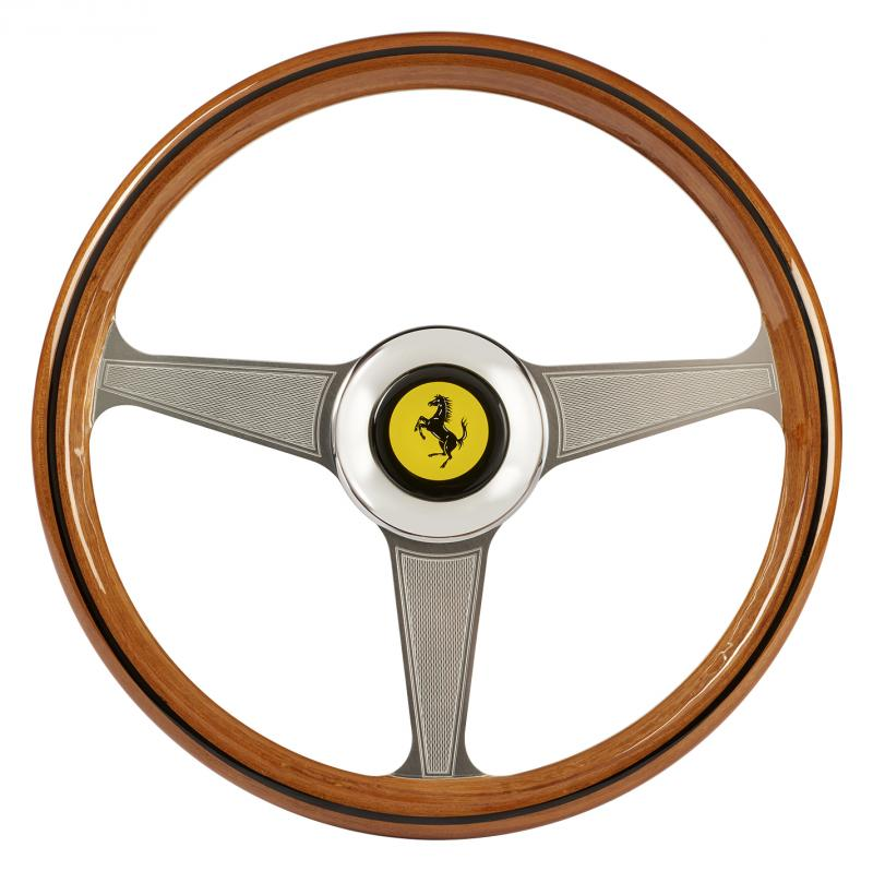 Un volante in legno a tre razze con il logo Ferrari al centro.