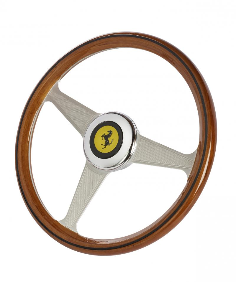 Un volante in legno a tre razze con il logo Ferrari al centro.