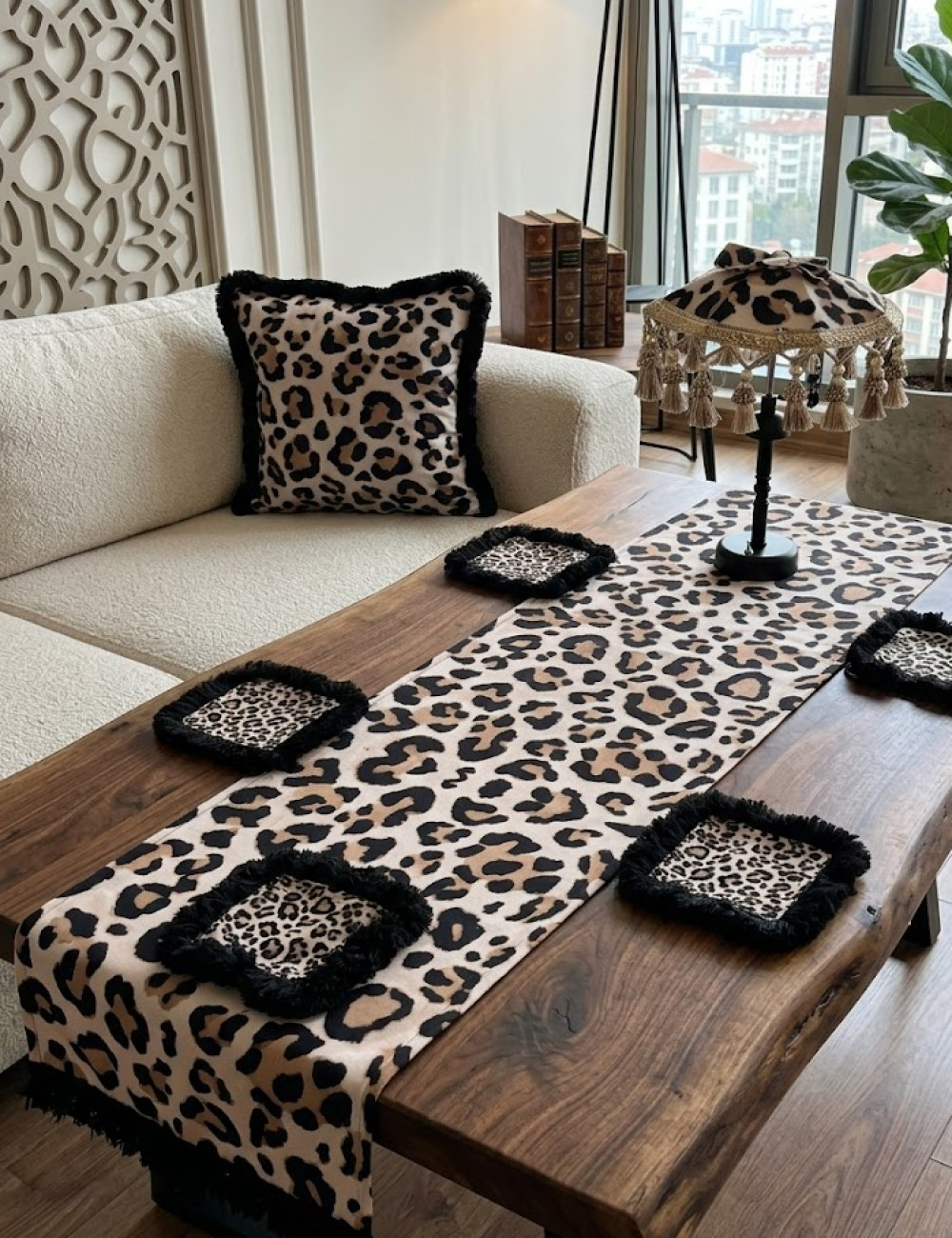 Ahşap masa üzerinde leopar desenli yastık, runner ve bardak altlığı.
