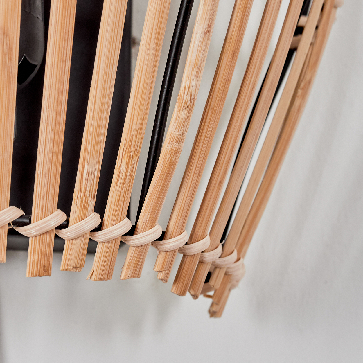 Detail eines Lampenschirms aus Bambusstäben und schwarzen Metallstreben.