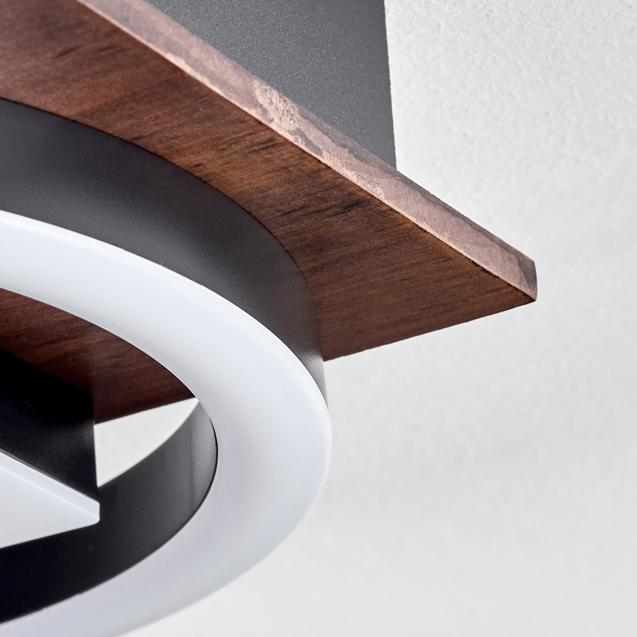 Ein Teil einer Lampe mit Holzdetail und weißem Ring vor weißem Hintergrund.