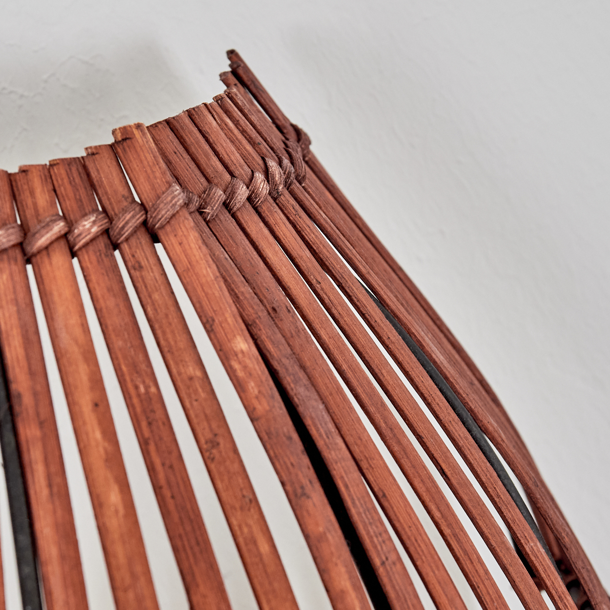 Brauner Korbstuhl-Detail mit vertikalen Streifen und geflochtenen Verbindungen.