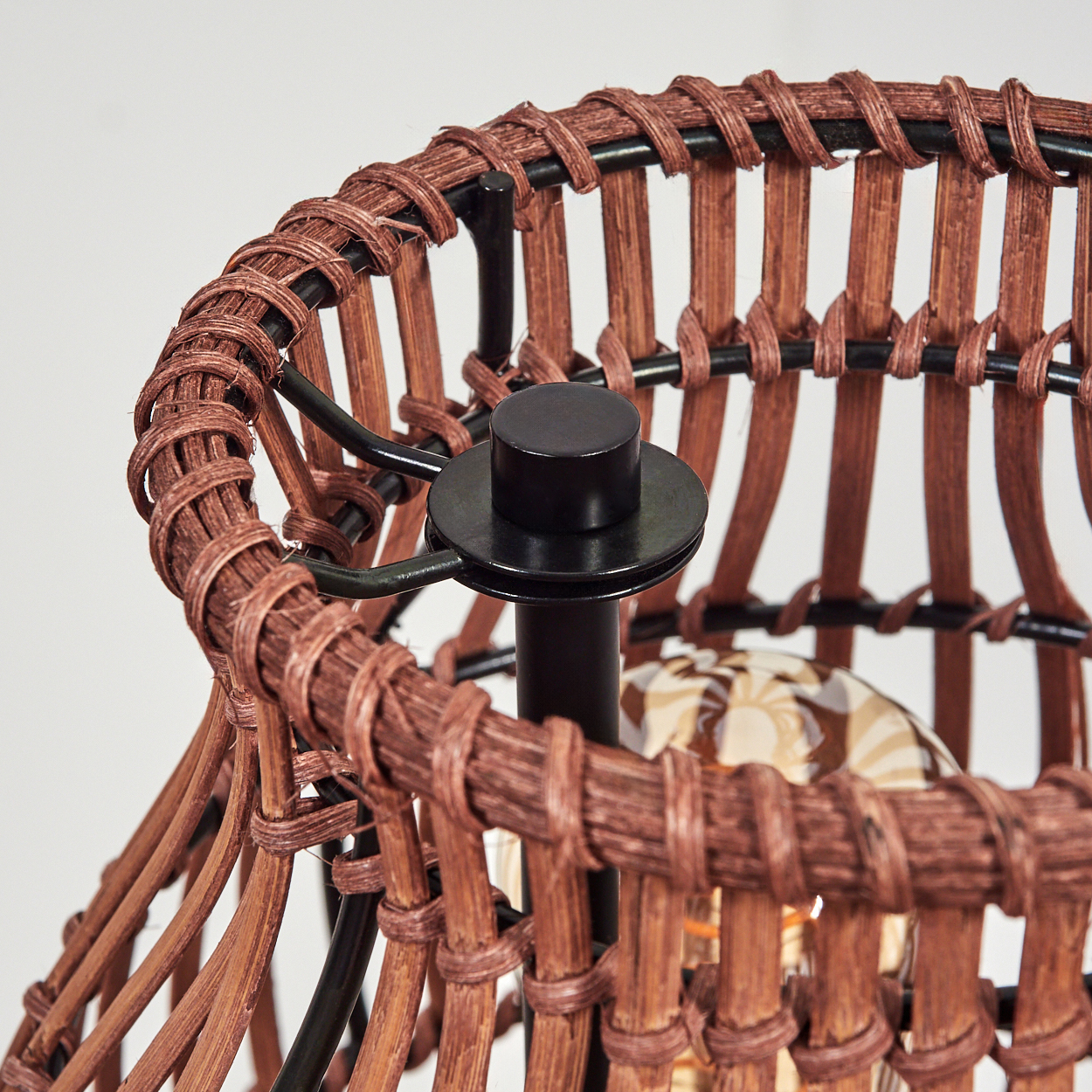 Nahaufnahme eines Lampenschirms aus braunem Rattan mit schwarzem Metallgestell.