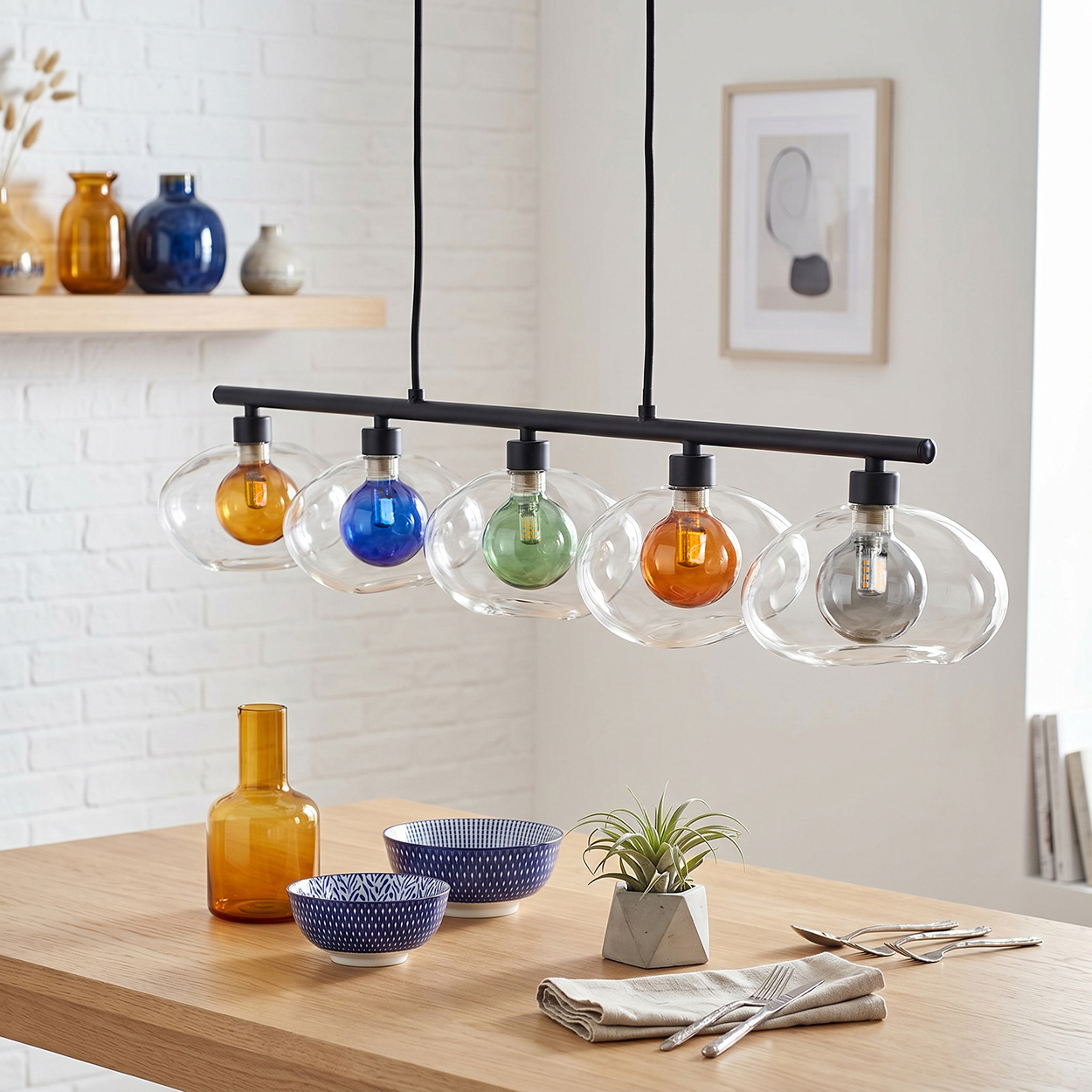 Pendelleuchte mit fünf Glaskolben, drei davon farbig (orange, blau, grün).