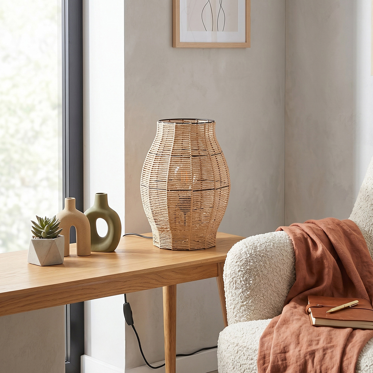 Eine gewebte Lampe steht auf einem Holztisch mit zwei Ziervasen und einer Pflanze.