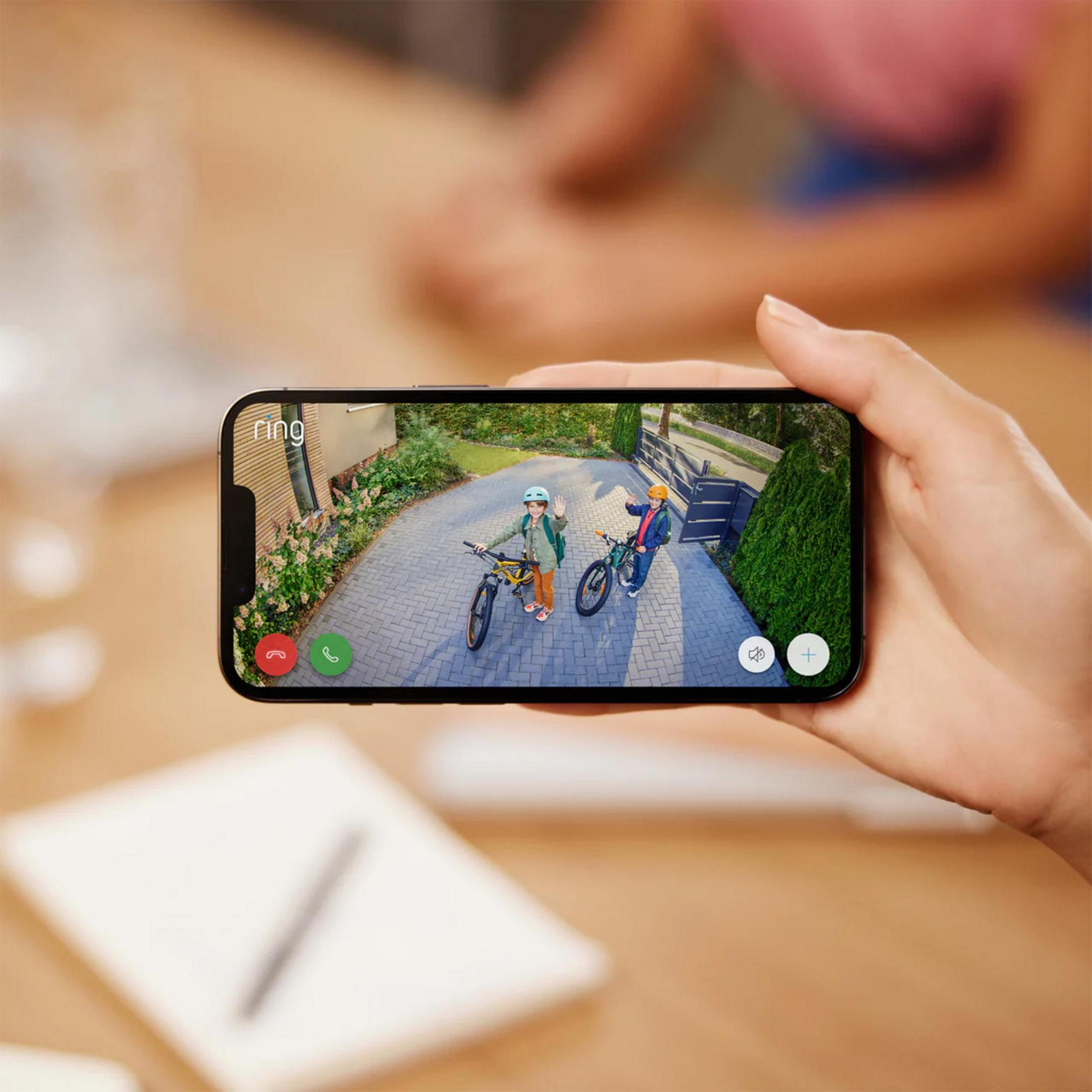 Twee kinderen op fietsen zwaaien voor een huis. Weergave op smartphone.