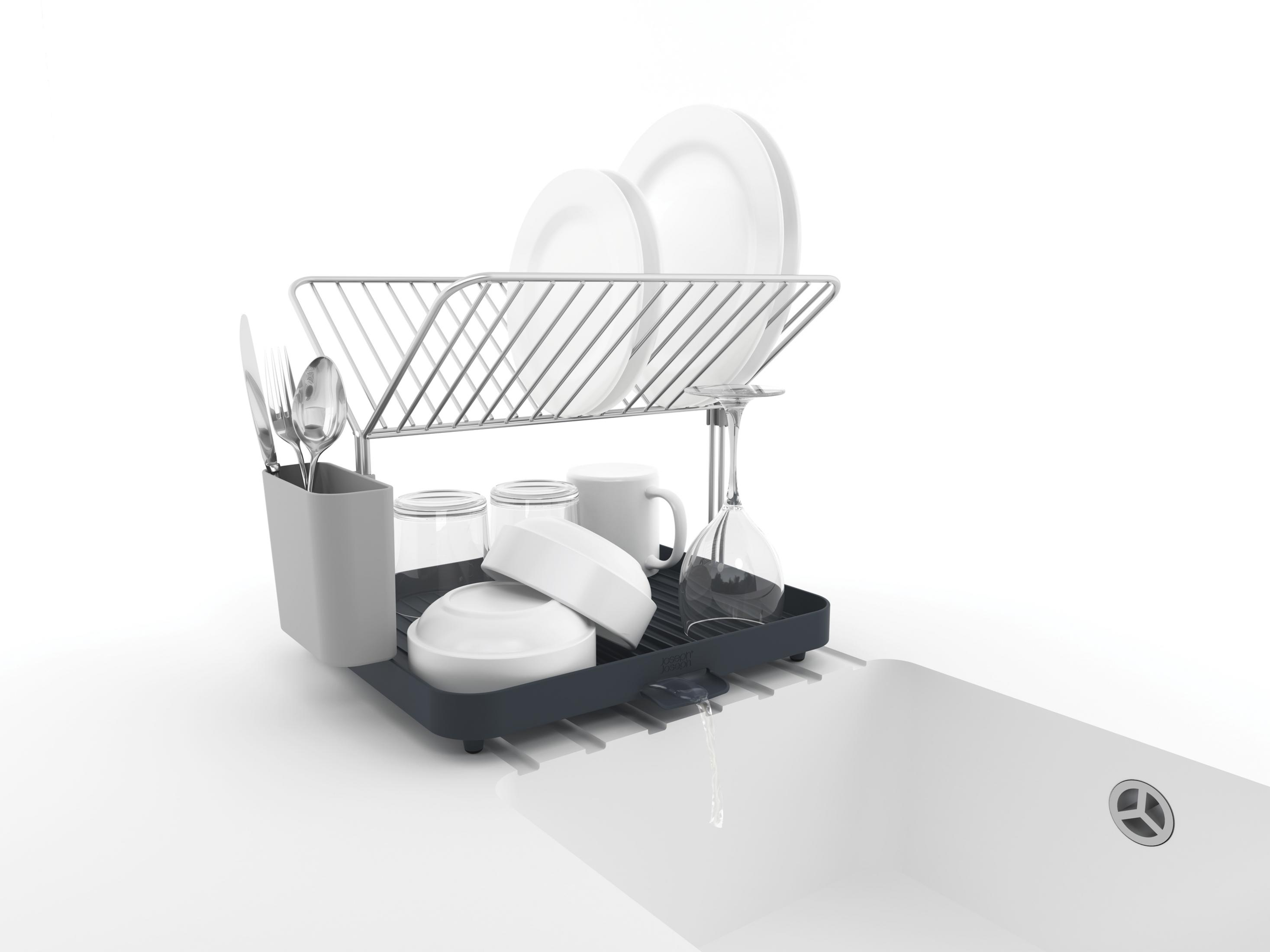 Un escurreplatos gris sostiene platos blancos, cuencos, tazas, vasos y cubiertos sobre un fregadero.