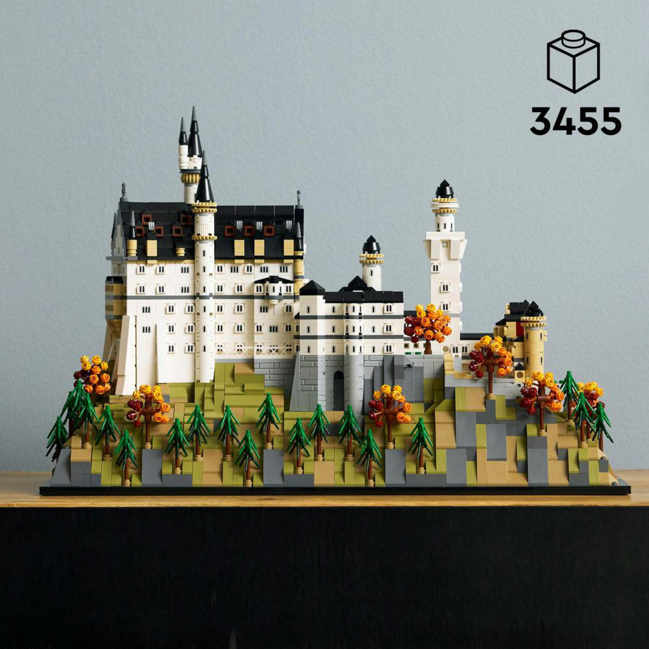 Un modelo de Lego de un castillo con torres y árboles sobre una base rocosa.