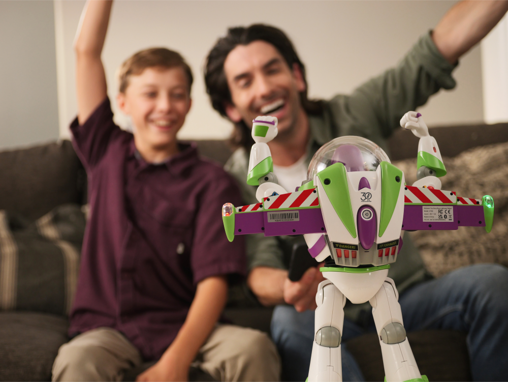Un niño y un hombre ríen y vitorean con un juguete de Buzz Lightyear.