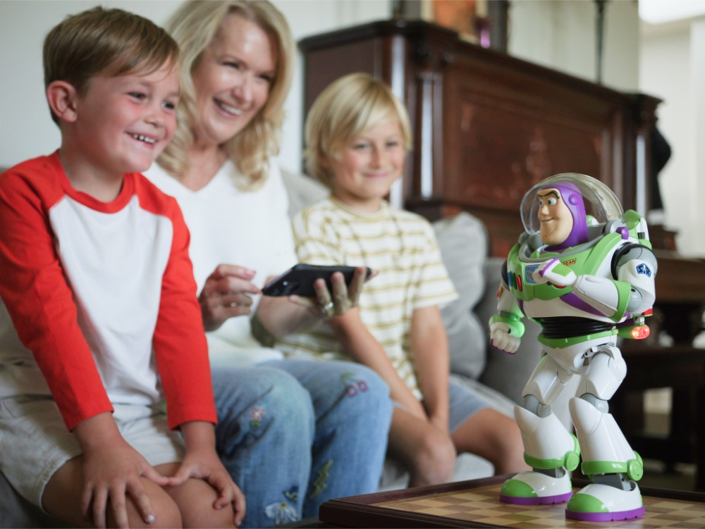 Un niño con camiseta de manga roja y una mujer sonríen al mirar un juguete de Buzz Lightyear.