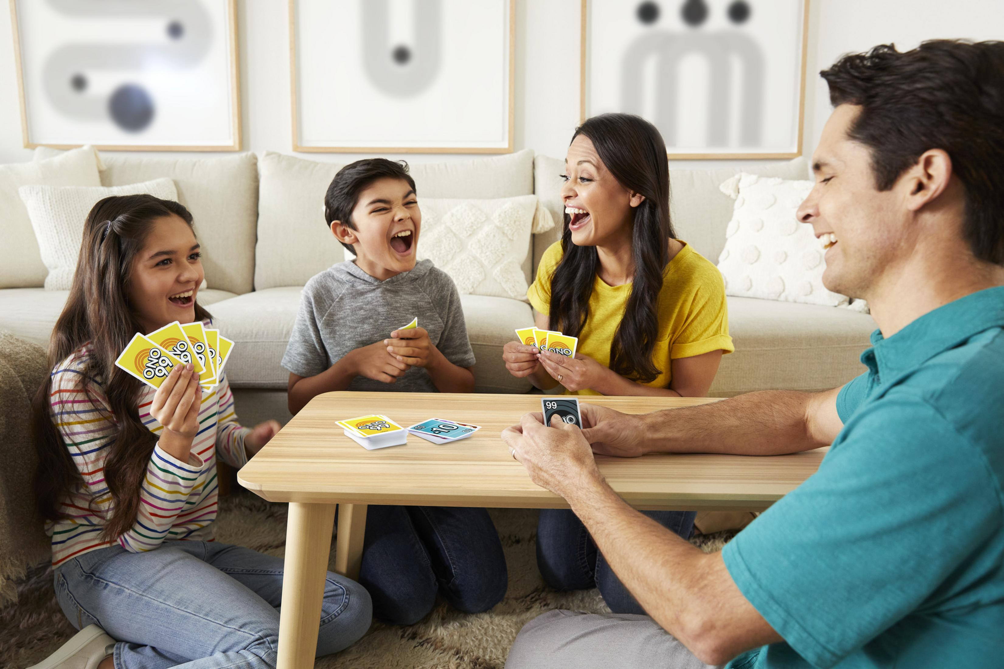Eine Familie spielt UNO im Wohnzimmer. Alle lachen und halten Karten.