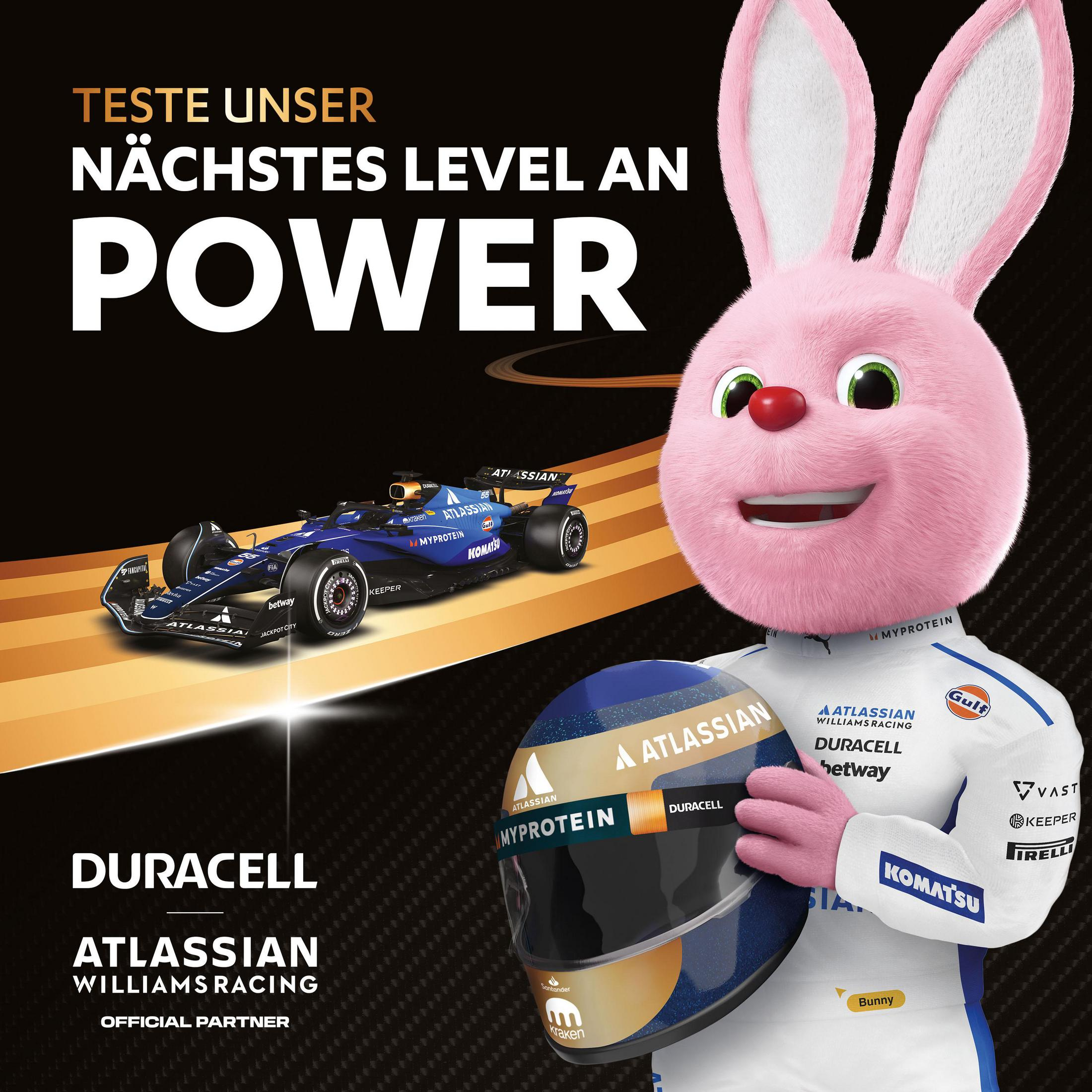 Un coniglio rosa tiene un casco davanti a un'auto di Formula 1. Testo: Prova il nostro prossimo livello di potenza.