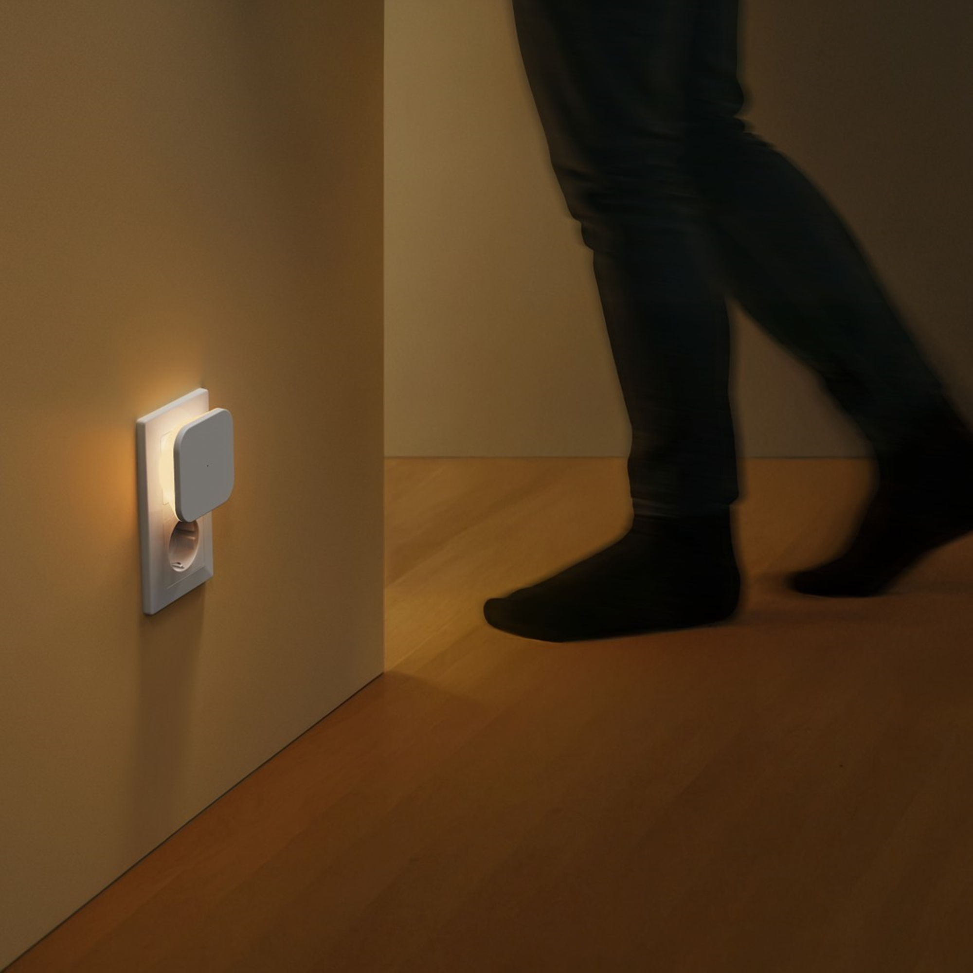 Ein Nachtlicht leuchtet neben einer Steckdose, während sich eine Person nähert.