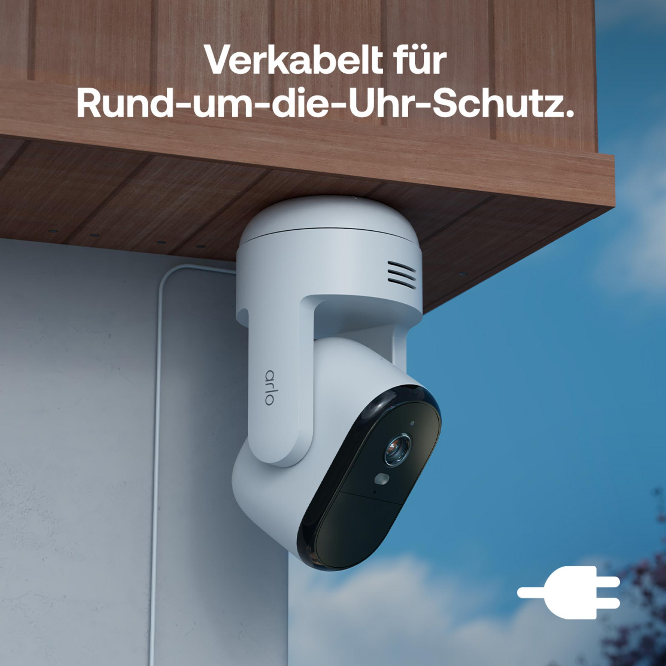 Caméra de sécurité Arlo blanche montée sur mur de maison, sous toit en bois.