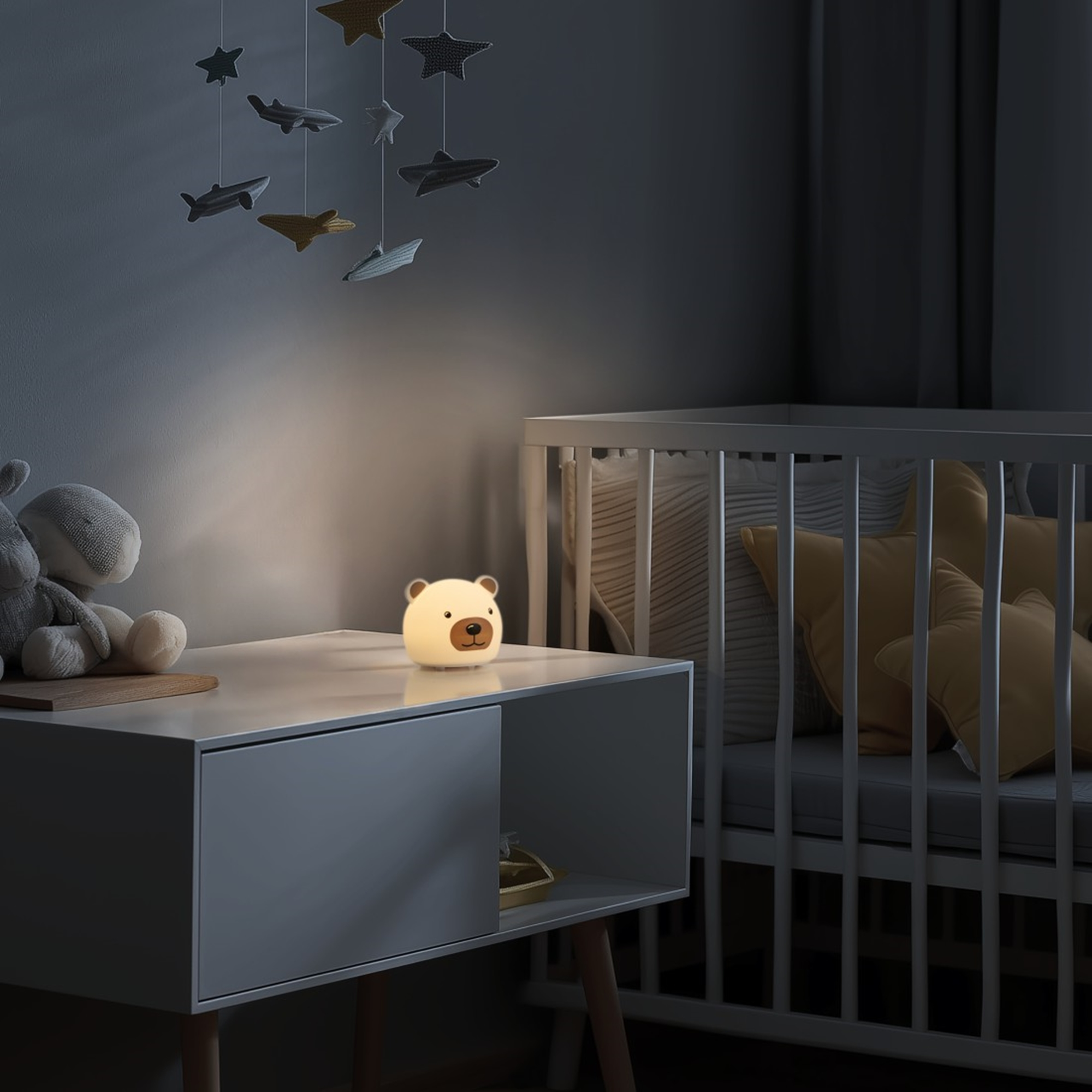 Ein niedlicher Nachtlicht-Bär leuchtet auf einem Nachttisch neben einem Babybett.