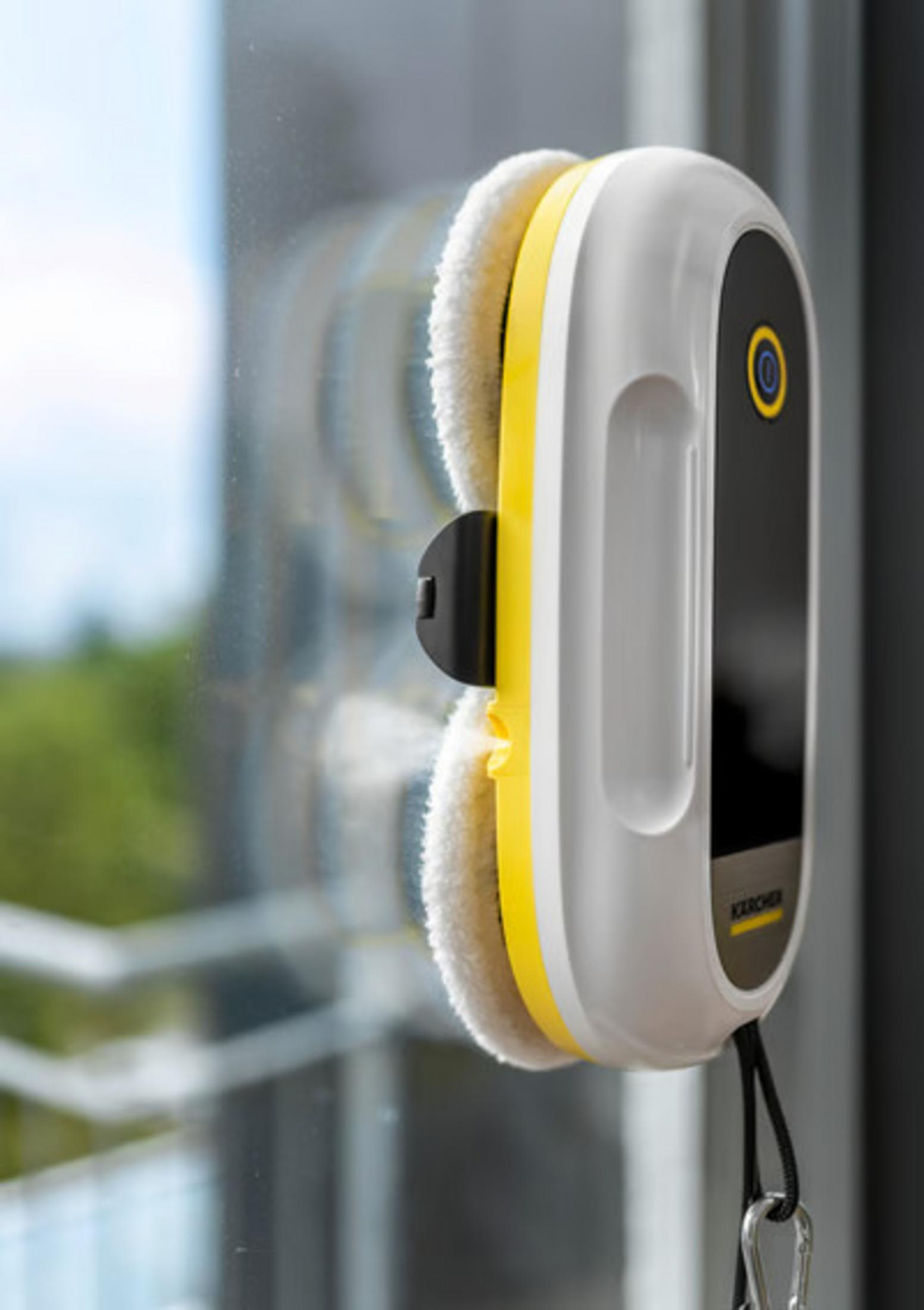 Ein weißer und gelber Fensterreinigungsroboter haftet an einem Fenster.