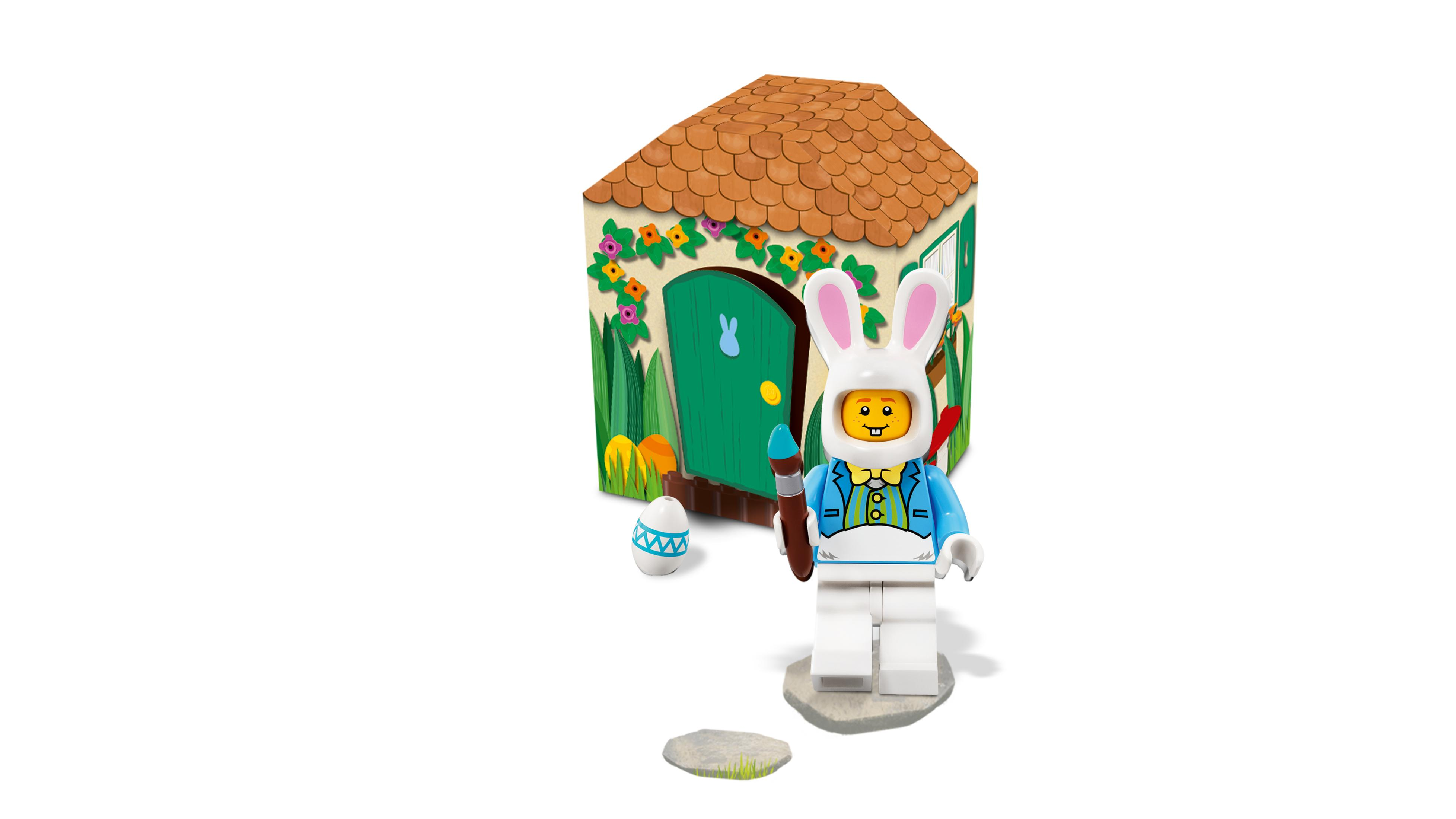 Un coniglio pasquale Lego con pennello e uovo davanti a una casa fiorita.