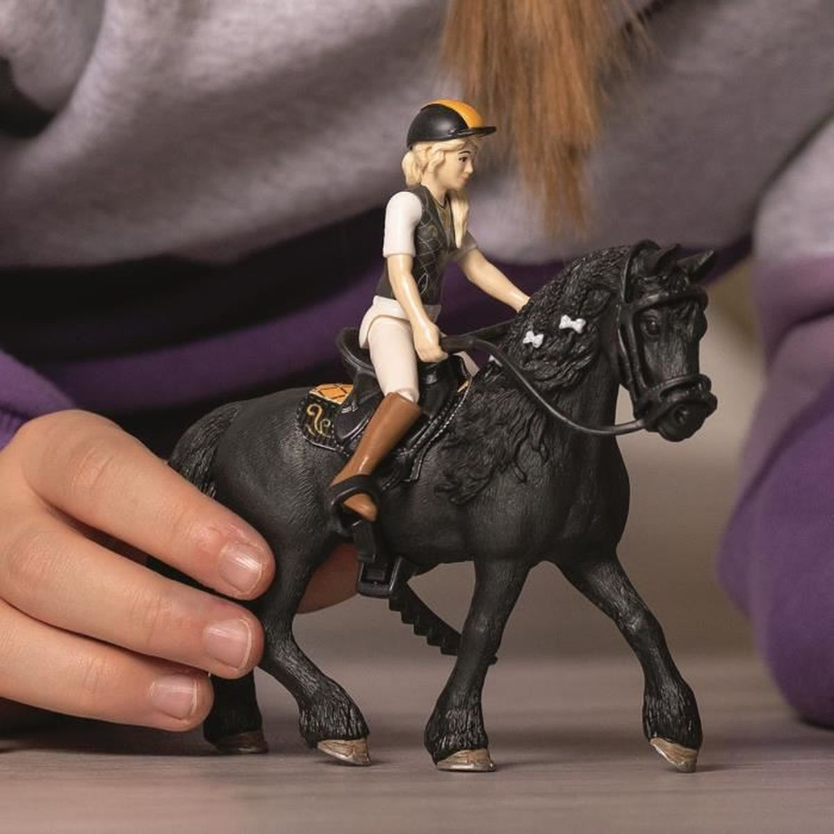 Un cavallo giocattolo e cavaliere. Il cavallo nero ha un cavaliere in gilet e casco.