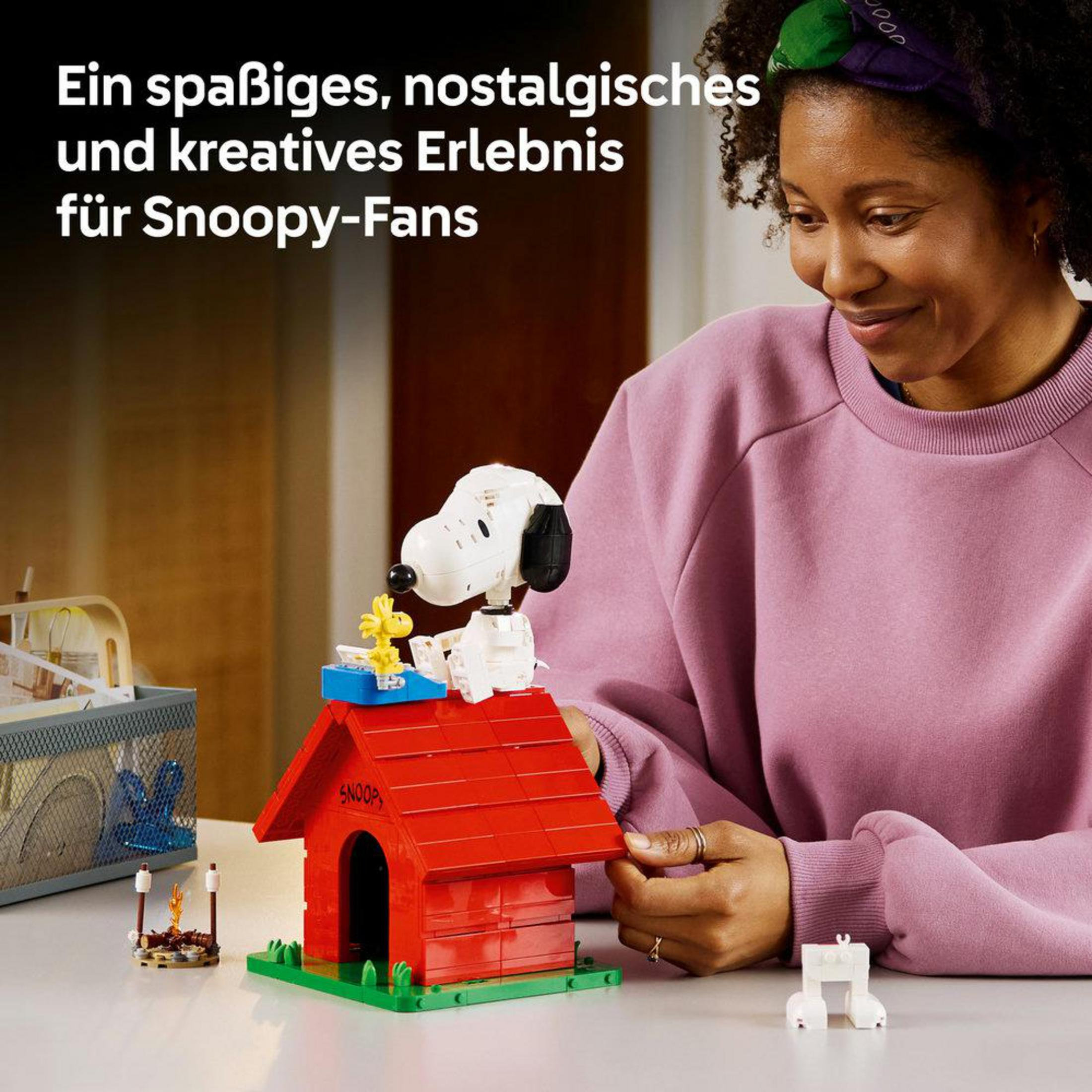 Donna costruisce la casa di Snoopy con i Lego. Un piccolo Woodstock siede sul tetto.
